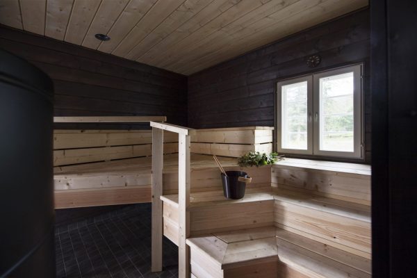 Sauna, jossa on vaaleat puupaneelit ja ikkuna, joka avautuu ulos luontoon.