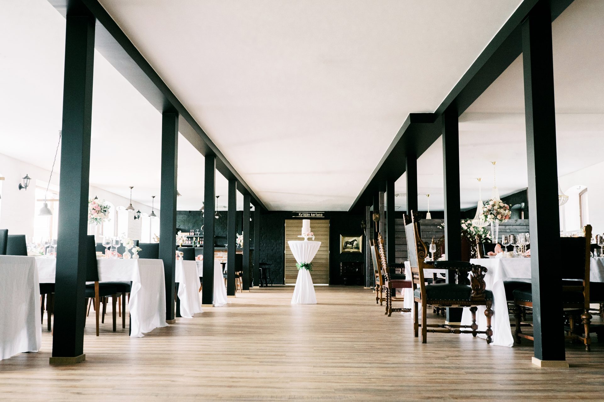 A bright and spacious restaurant area with white tables and wooden pillars.